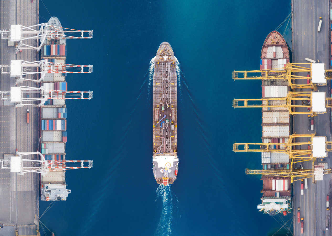 LCL Shipping Containers on a dock with a container ship passing through