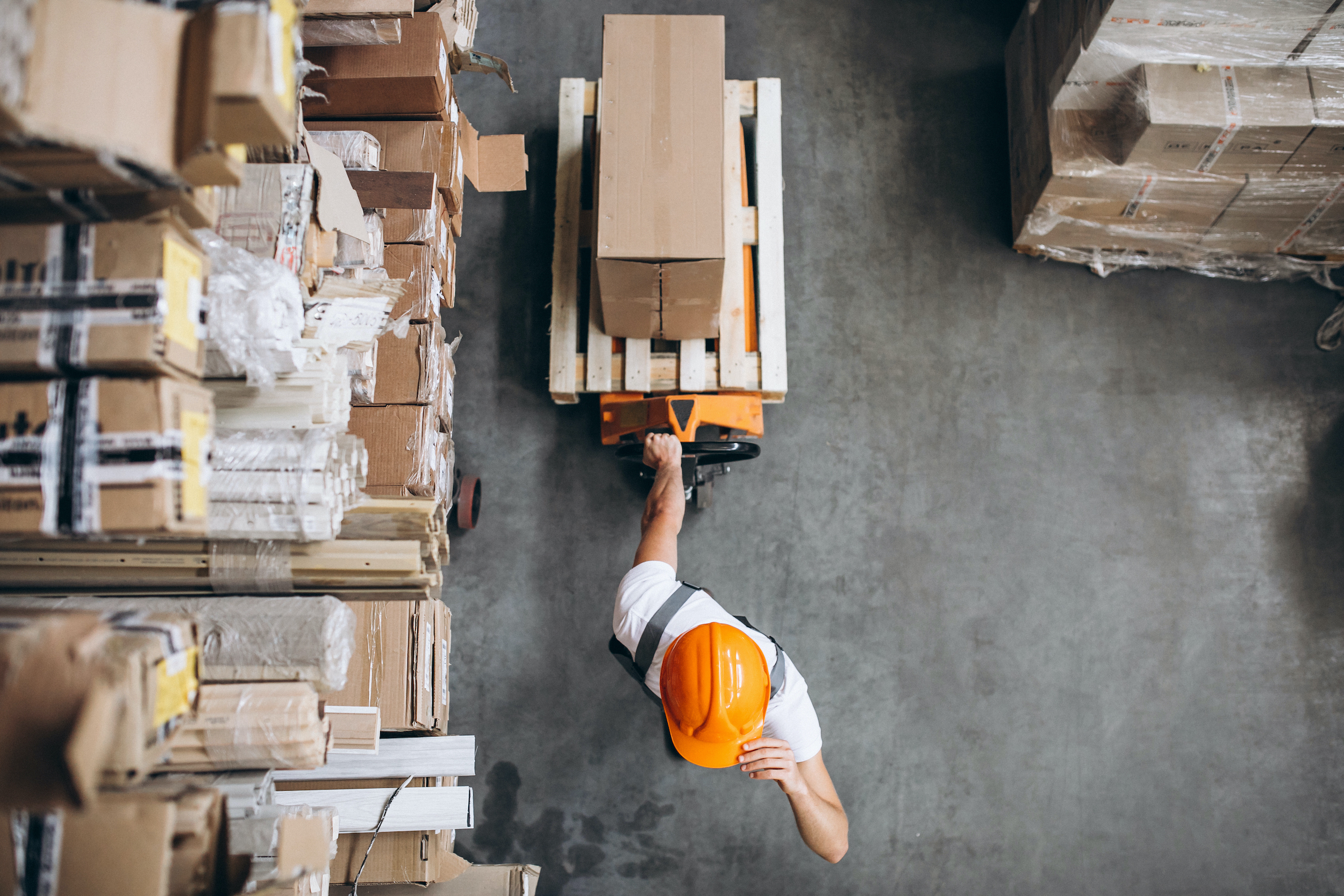 Young man in warehouse moving pallet containers on a pump truck