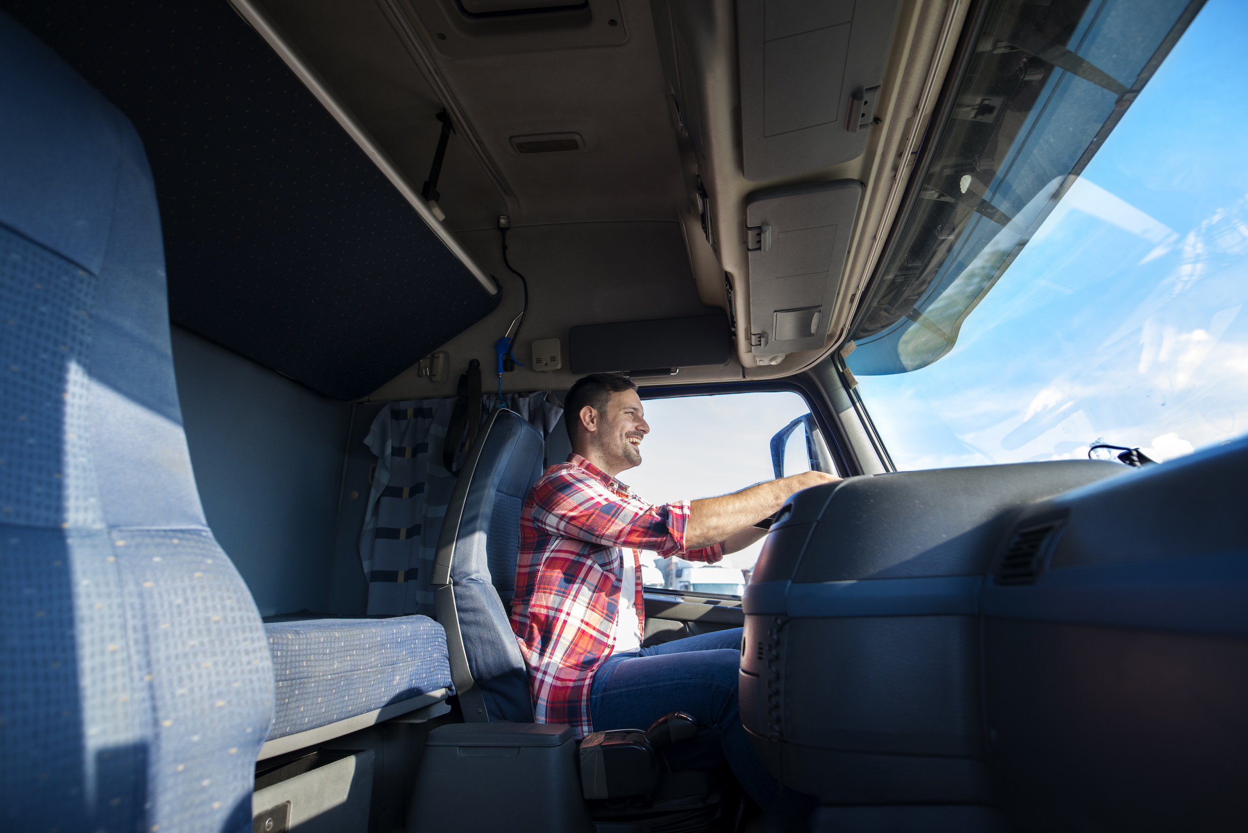 professional truck driver in cab, smiling whilst driving