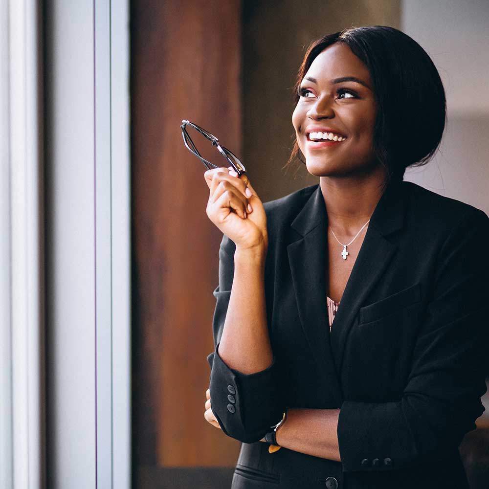 Woman looking out of window in office, smiling